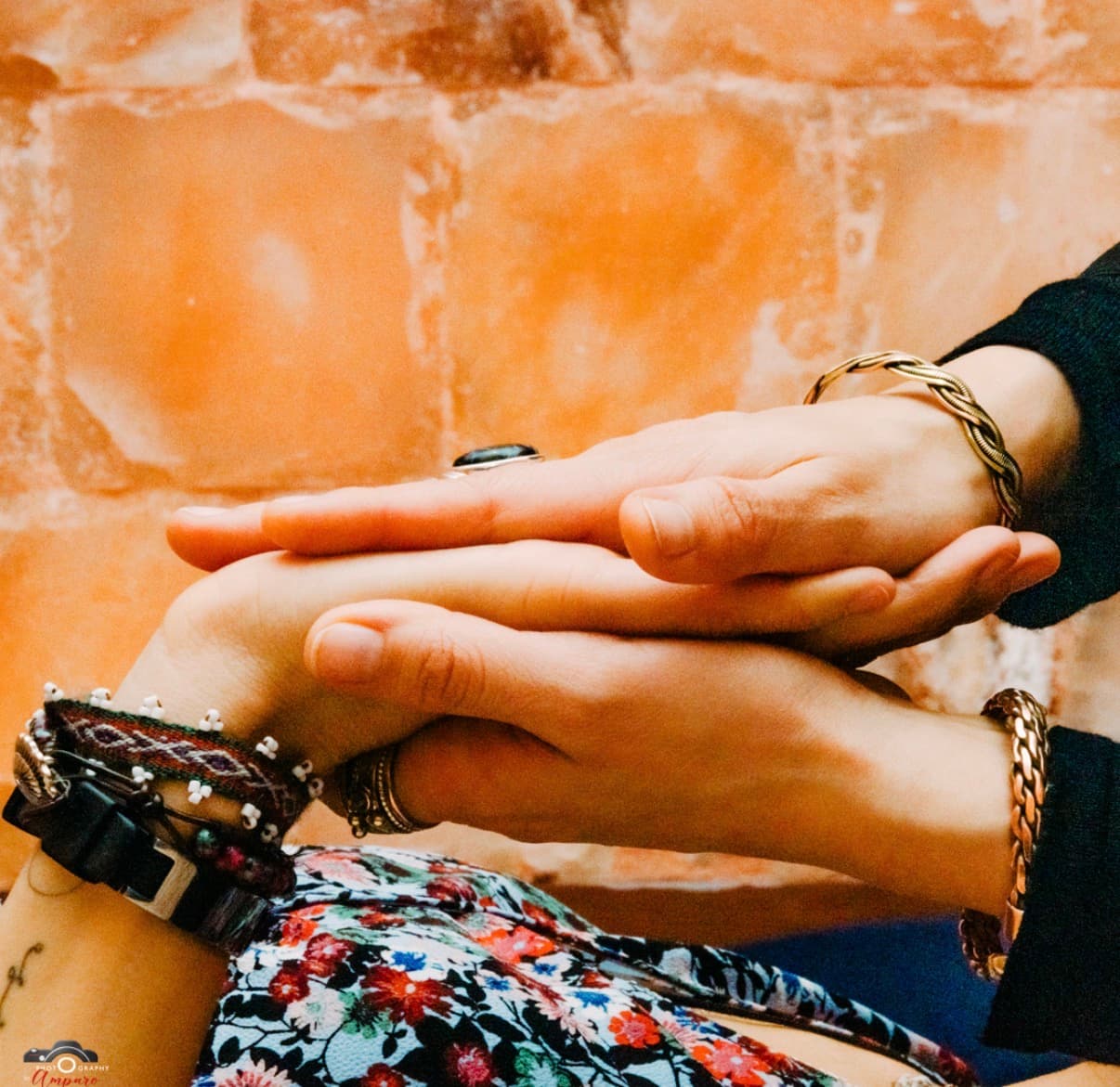Two people's hands clasped together against a terracotta tile wall, bracelets and rings visible; client-selected for the methods page (source: Handholding.jpg)
